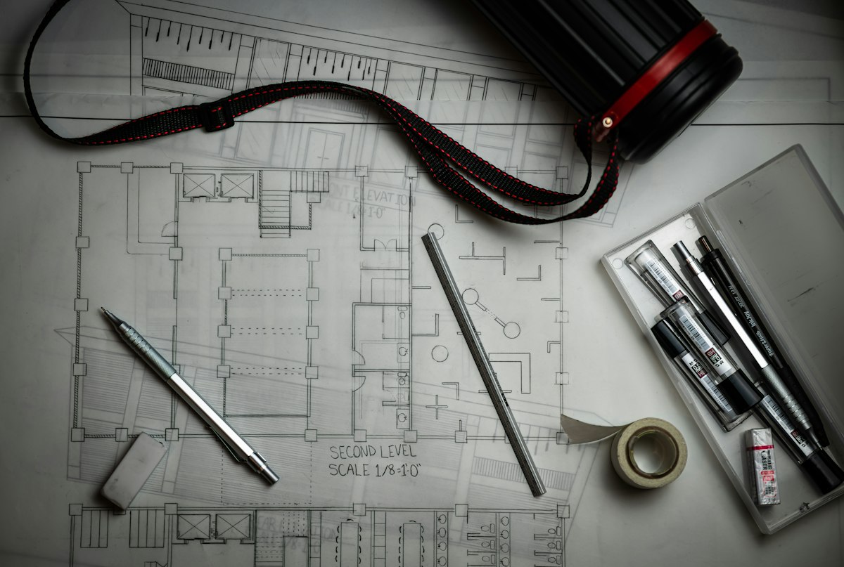 Architectural plans, drafting pencils and scale ruler for cooperative society plot maps in Karachi